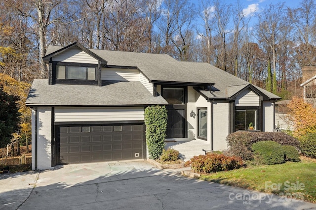 view of front of house with a garage, concrete driveway, brick siding, and roof with shingles