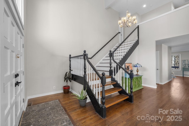 foyer entrance featuring dark wood-style floors, a chandelier, baseboards, and stairs