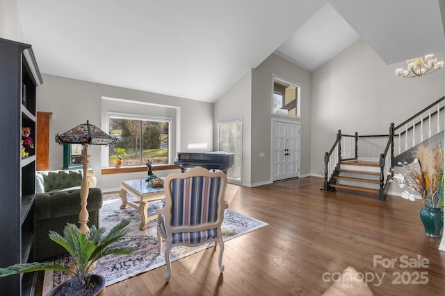 living room featuring high vaulted ceiling, a notable chandelier, dark wood-type flooring, baseboards, and stairs