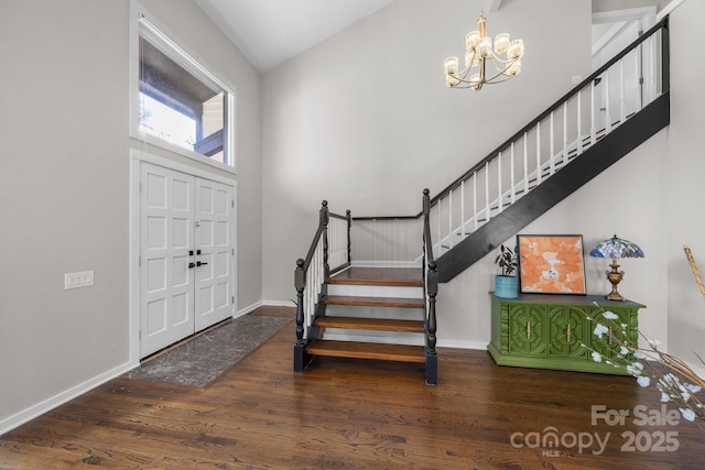 foyer with an inviting chandelier, baseboards, stairway, and dark wood-style flooring