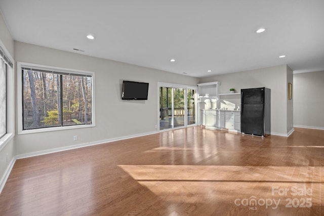 unfurnished living room with baseboards, wood finished floors, visible vents, and recessed lighting