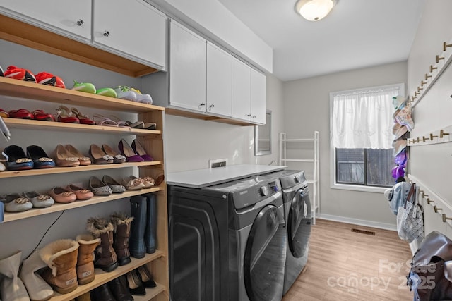 laundry room featuring light wood finished floors, cabinet space, visible vents, baseboards, and washing machine and dryer