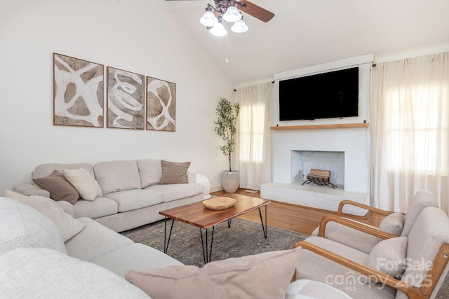 living room with ceiling fan, high vaulted ceiling, wood finished floors, and a fireplace