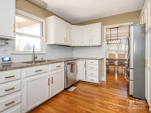 kitchen with visible vents, light wood finished floors, a sink, stainless steel appliances, and white cabinetry