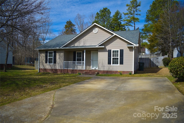 view of front of home with a trampoline, a porch, a front yard, and fence