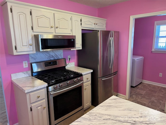 kitchen with baseboards, washer / clothes dryer, stainless steel appliances, light countertops, and a textured ceiling