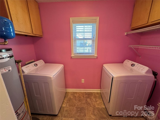 washroom featuring washer and clothes dryer, cabinet space, gas water heater, and baseboards