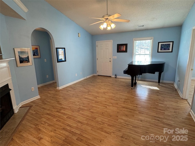 foyer with visible vents, arched walkways, a fireplace, and light wood finished floors