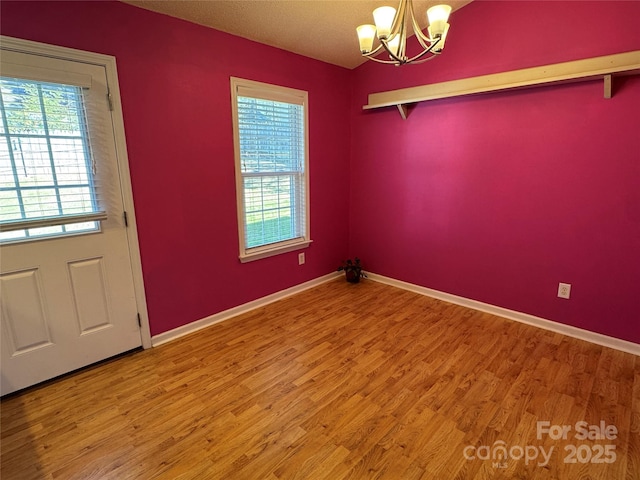 unfurnished dining area with a chandelier, baseboards, and wood finished floors