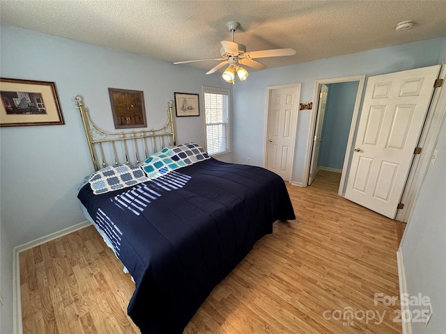 bedroom featuring ceiling fan, light wood-style flooring, and a textured ceiling