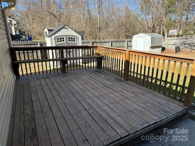 wooden deck with an outbuilding, a shed, and a fenced backyard