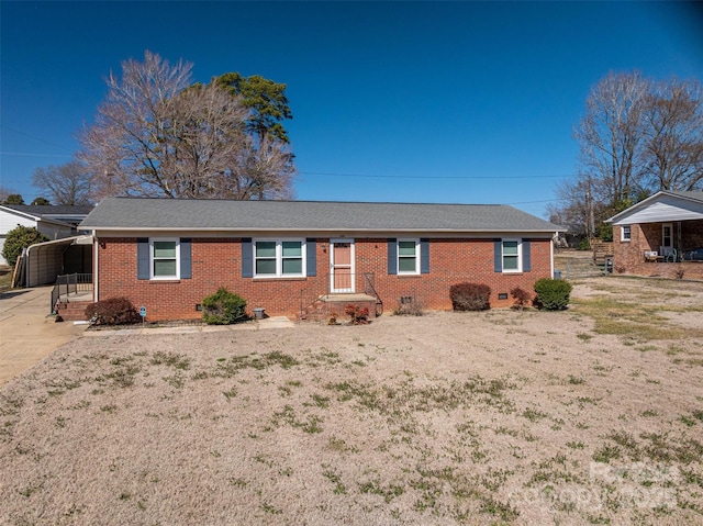 ranch-style house with crawl space, roof with shingles, a carport, and brick siding