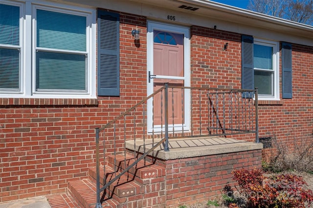 property entrance featuring visible vents and brick siding