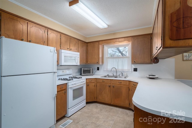 kitchen with white appliances, visible vents, brown cabinets, light countertops, and a sink