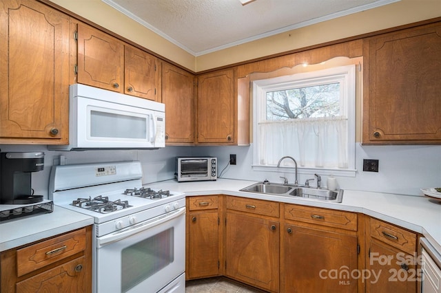 kitchen featuring white appliances, light countertops, a sink, and brown cabinetry