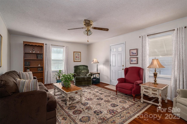 living area featuring a ceiling fan, dark wood-style flooring, a textured ceiling, and baseboards