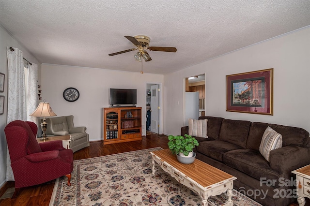 living area featuring dark wood-style flooring, ceiling fan, a textured ceiling, and baseboards