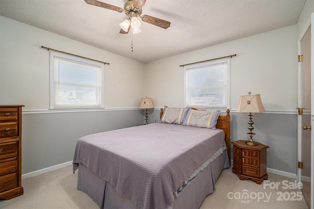 bedroom with light carpet, a textured ceiling, a ceiling fan, and baseboards