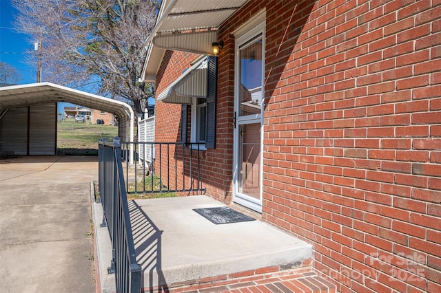 doorway to property featuring a carport and brick siding