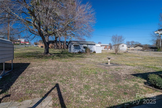 view of yard featuring a residential view, an outdoor structure, fence, and a shed