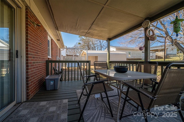 deck featuring a storage shed, outdoor dining space, and an outdoor structure