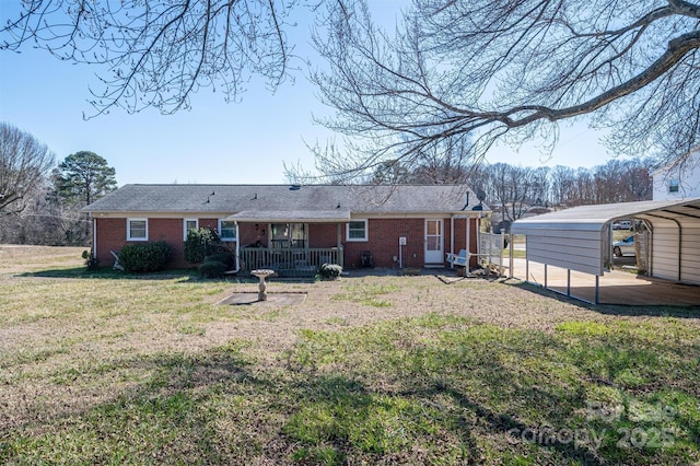 rear view of house featuring brick siding, a carport, and a yard