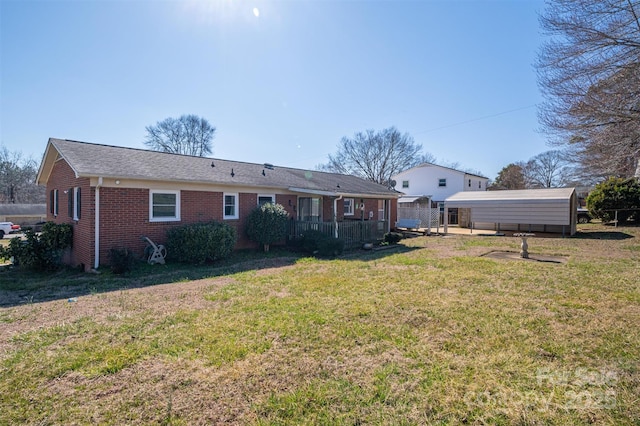 rear view of house featuring a lawn and brick siding