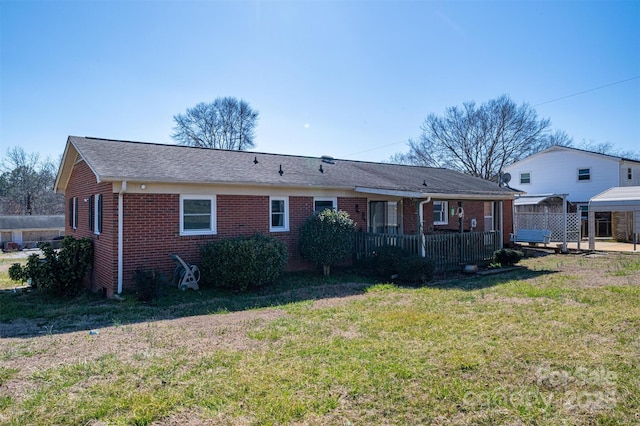 back of property featuring a wooden deck, a lawn, and brick siding