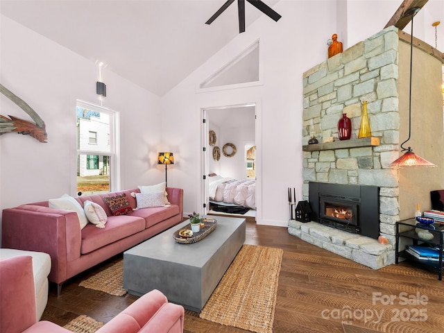 living room with dark wood-style floors, high vaulted ceiling, a stone fireplace, and a ceiling fan