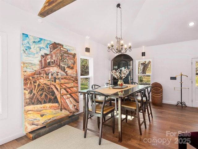 dining space with a notable chandelier, vaulted ceiling, wood finished floors, and baseboards