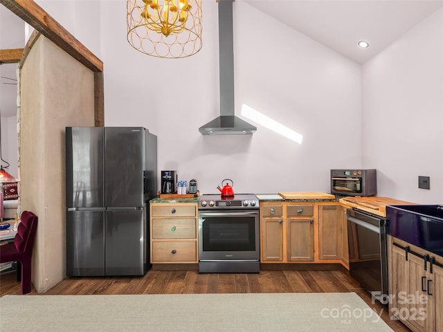 kitchen with dark wood-type flooring, light countertops, appliances with stainless steel finishes, wall chimney range hood, and an inviting chandelier