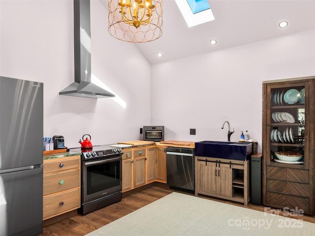 kitchen featuring a sink, appliances with stainless steel finishes, wall chimney range hood, dark wood finished floors, and pendant lighting