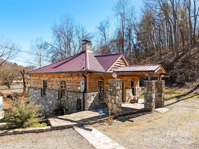view of front of property with metal roof, stone siding, and a chimney