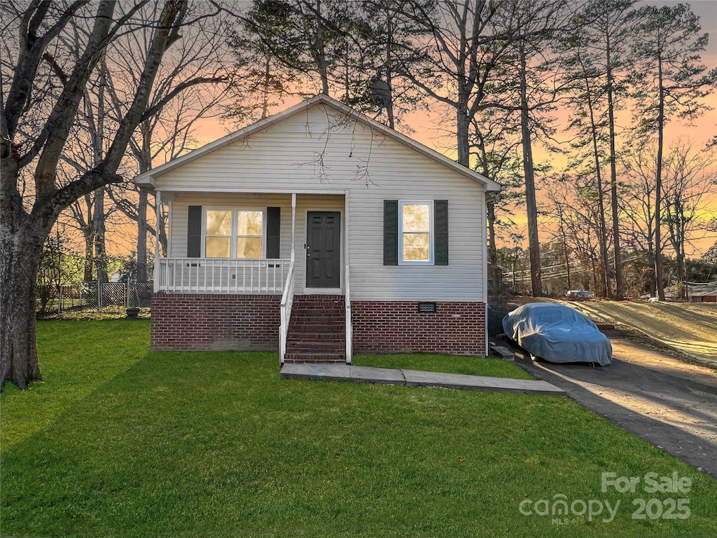 bungalow with crawl space, a porch, and a lawn