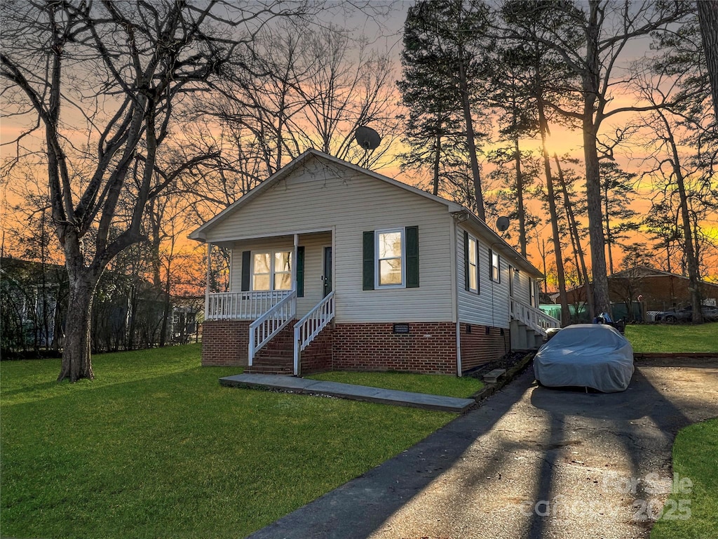 bungalow-style home with covered porch, a front lawn, crawl space, and stairway