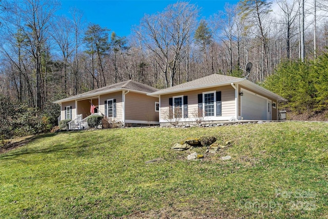 ranch-style house featuring an attached garage, a porch, a front yard, and a view of trees