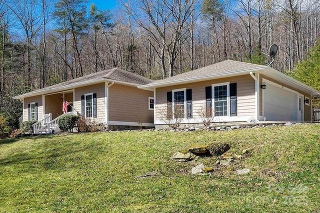 ranch-style home with a garage, a forest view, and a front yard