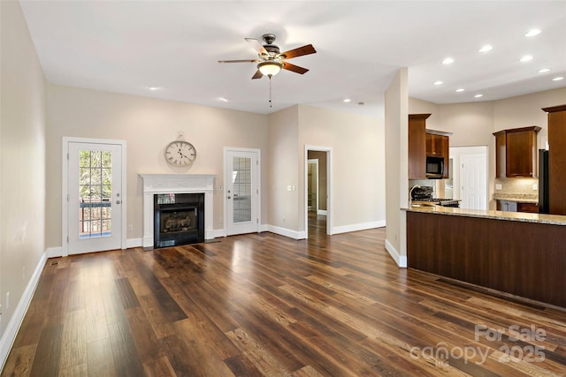 kitchen featuring black appliances, open floor plan, dark wood finished floors, decorative backsplash, and light stone countertops