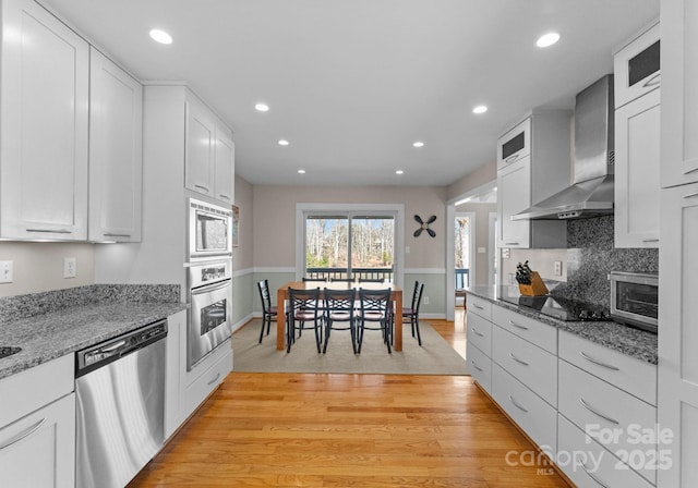 kitchen with recessed lighting, wall chimney range hood, and stainless steel appliances