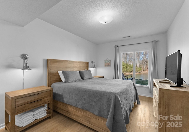 bedroom featuring a textured ceiling, visible vents, and light wood-type flooring