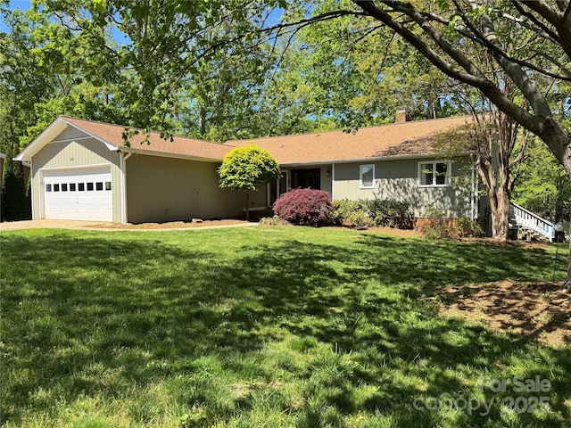 single story home with an attached garage, a chimney, a shingled roof, and a front yard