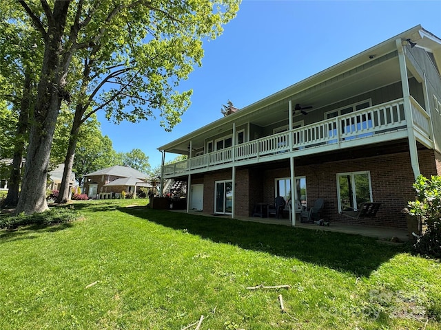 back of property featuring brick siding, a ceiling fan, and a lawn