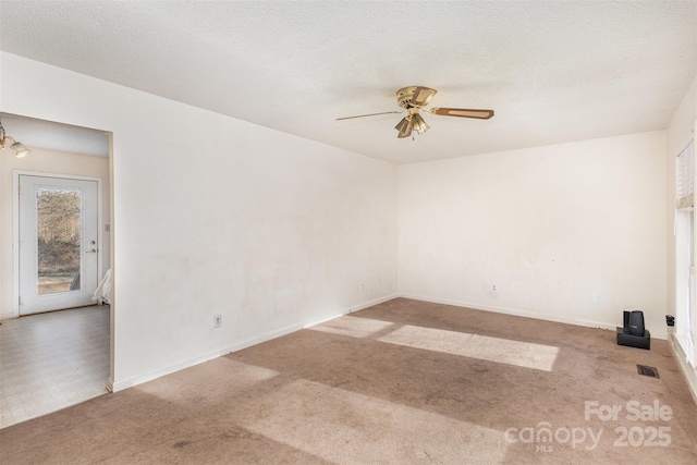 carpeted spare room featuring a textured ceiling, baseboards, visible vents, and a ceiling fan