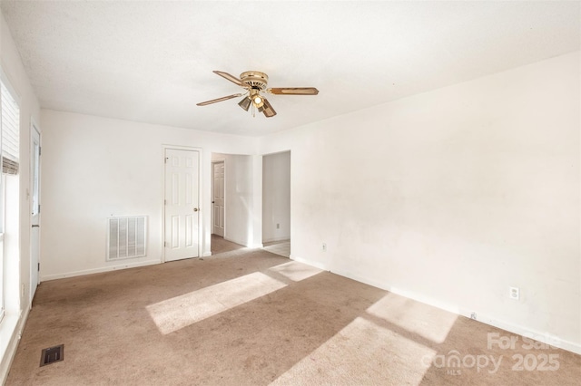 unfurnished room with light carpet, baseboards, visible vents, and a ceiling fan