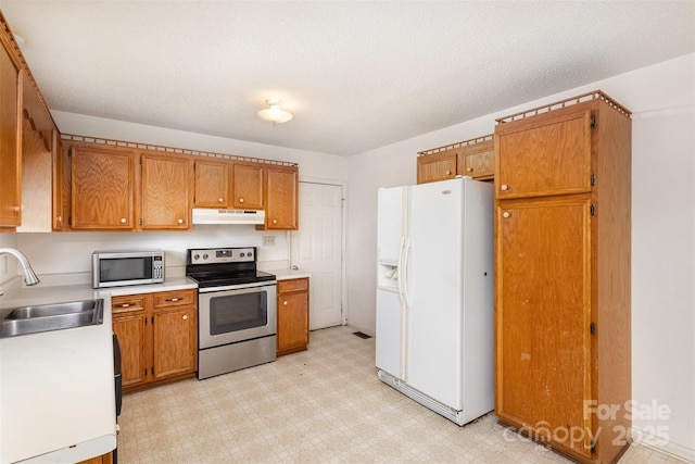 kitchen with a sink, under cabinet range hood, stainless steel appliances, and light floors