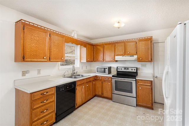 kitchen featuring appliances with stainless steel finishes, brown cabinets, light floors, under cabinet range hood, and a sink