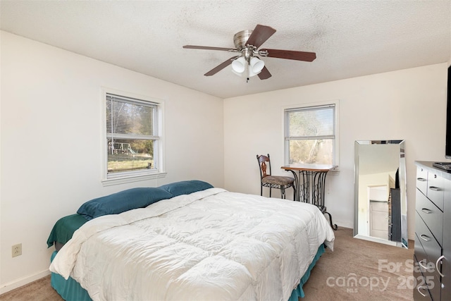 bedroom featuring light carpet, ceiling fan, a textured ceiling, and baseboards