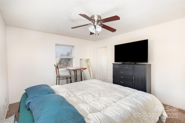 carpeted bedroom featuring ceiling fan, baseboards, and a textured ceiling