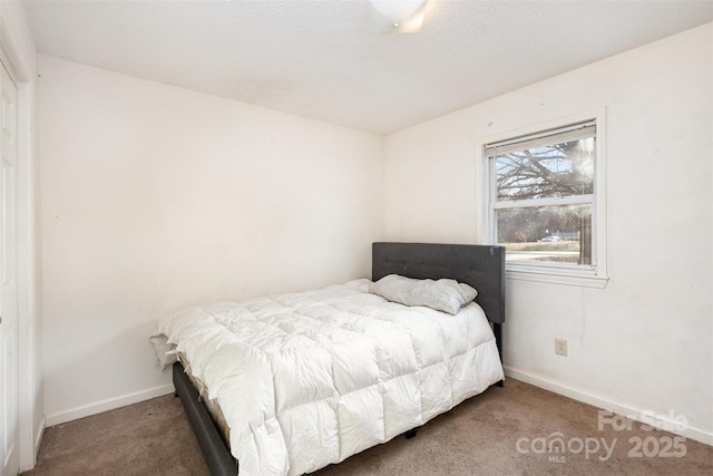 carpeted bedroom featuring a textured ceiling and baseboards