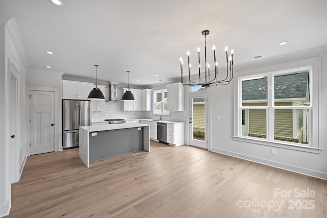 kitchen featuring white cabinets, a center island, hanging light fixtures, stainless steel appliances, and light countertops